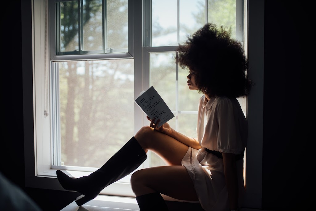 Girl Reading a book beside the window
